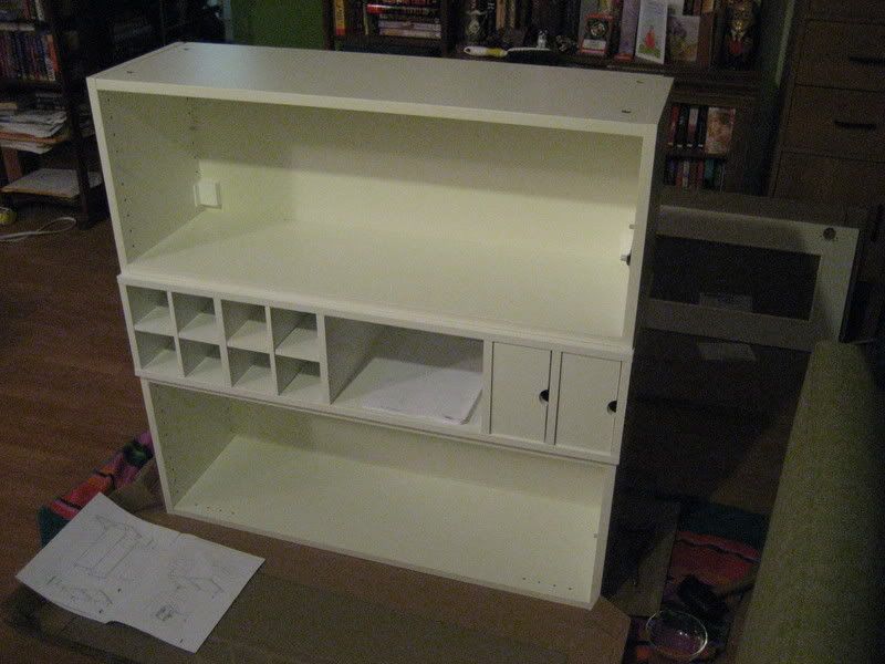 3 kitchen cabinets stacked. Middle cabinet has 8 wine cubbies and 2 sideways drawers.