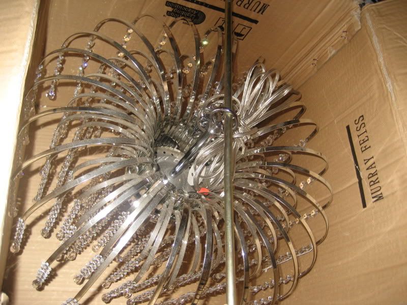 crystal chandelier hanging in a box from a bent threaded rod